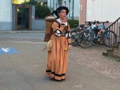 Eine Frau in historischer Kleidung läuft eine Straße entlang.