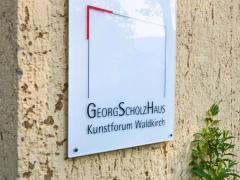 Schild auf dem "GeorgScholzHaus" steht.