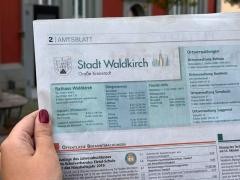Eine Person hält das Amtsblatt vor dem Waldkircher Rathaus hoch.