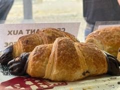 Zwei Schokocroissants liegen in einer Auslage.
