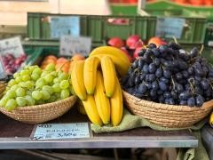 Verschiedenes Obst steht auf einem Marktstand. Darunter Trauben und Bananen.