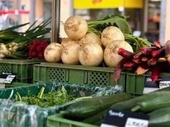 Verschiedenes Gemüse liegt auf einem Markstand. Unter anderem Mairüben und Gurken.