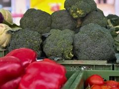 Brokkoli und rote Paprika liegen auf einem Marktstand.