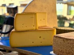 Verschiedene Käse liegen auf einem Marktstand.