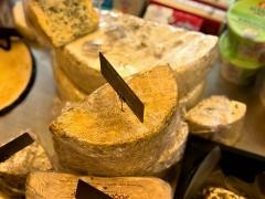 Verschiedene Käsesorten liegen in einem Marktstand.