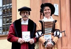Ein Mann und eine Frau in historischer Kleidung halten je ein Exemplar der Broschüre des Stadtführerdiploms