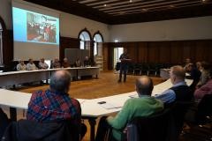 Im Bürgersaal des Waldkircher Rathaus sitzen mehrer Leute um einen Tisch. Eine Person steht in der Mitte und hält einen Vortrag.