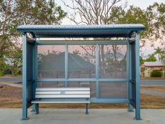 Haltestellenhäuschen, im Hintergrund ist ein Sonnenuntergang.