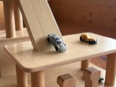 Ein Spielzeugauto steht auf einer Holzrutsche.
