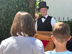 Zwei Kinder stehen vor einem Orgelspieler.