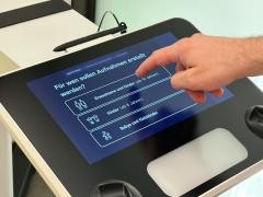 Eine Person wählt etwas auf einem Display aus.