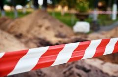 Ein Absperrband in rot und weiß hängt quer über eine Straße.