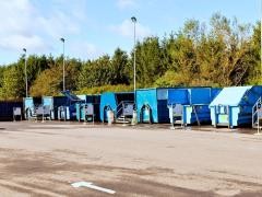 Auf einem Recylinghof stehen blaue Container.