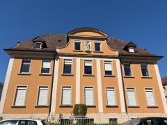 Vor blauem Himmel steht das orangene Josefshaus.