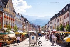Blick auf den Wochenmarkt in Waldkirch Das Bild zeigt einen Blick auf den Wochenmarkt bei Sonnenschein. Im Hintergrund sieht man den Kandel, im Vordergrund das Verkehrsschild mit der Schrift Marktplatz