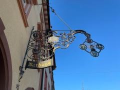 Blick auf die Fassade des Rathauses und das schmiedeeiserne Schild mit den Wappen aller Stadtteile.