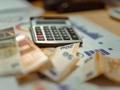 Auf einem Tisch liegen Geldscheine und ein Taschenrechner